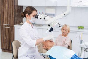 Family cosmetic dentistry allows female dentist having an ongoing dental check with a mother with her daughter.